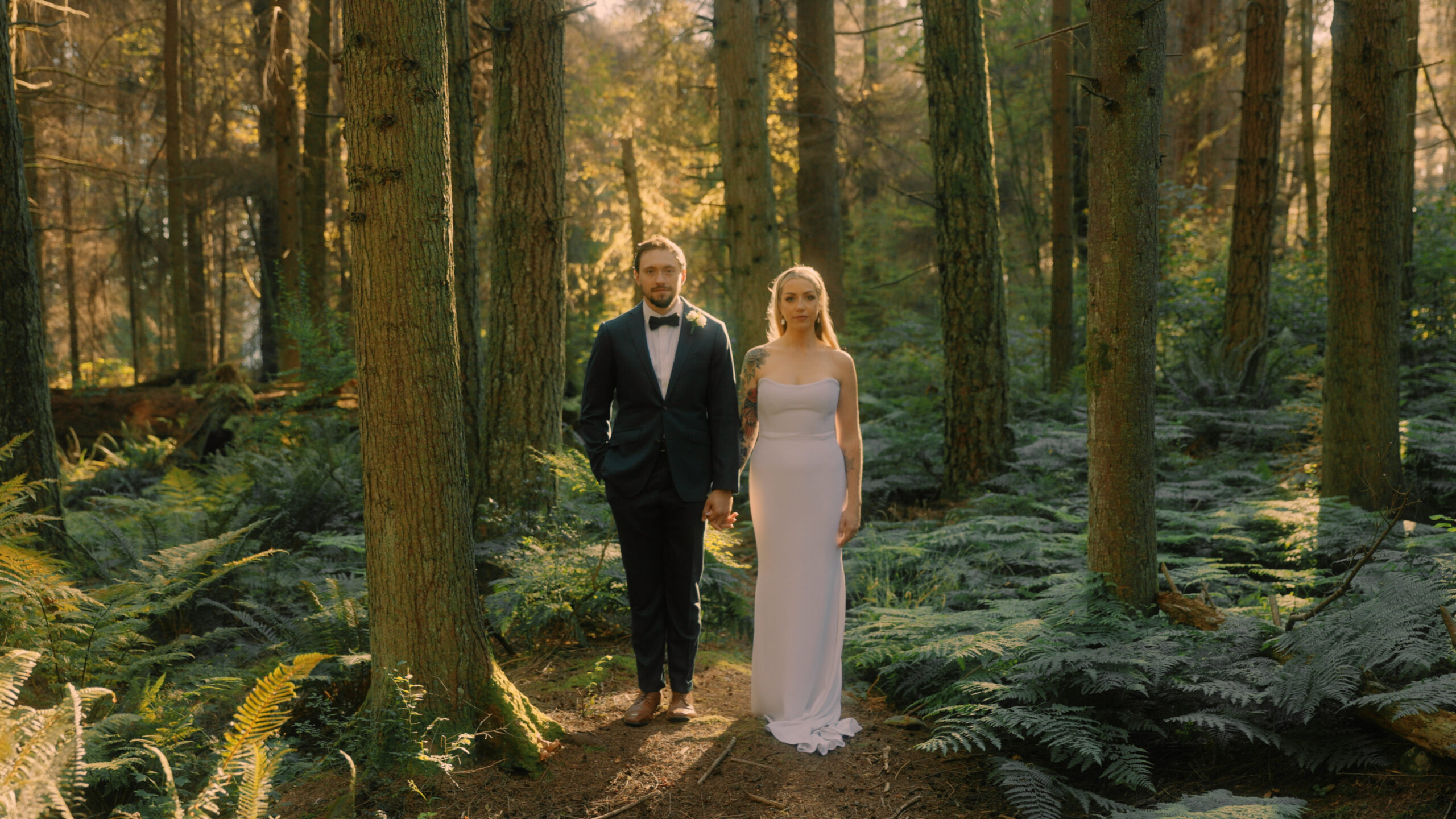 Laura and Xaiver stand side by side in the forest in Stanley Park